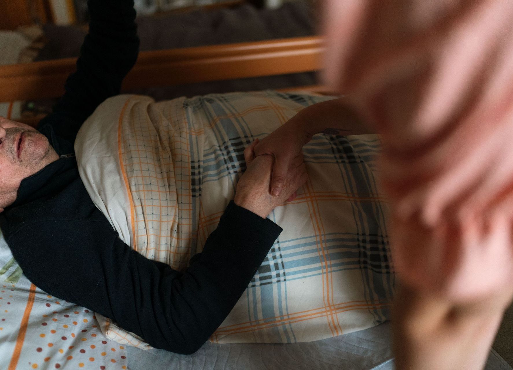 A caregiver holding hands with a senior adult, providing support and reassurance at home.